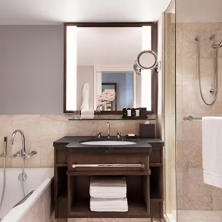 Four Seasons Hotel Sydney Exterior photo The photo shows a modern and stylish bathroom. It features a bathtub on the left side, a wooden vanity with a sink in the center, and a large mirror above it. To the right, there is a glass shower enclosure with a showerhead mounted on the wall. The 