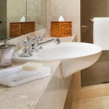 Four Seasons Hotel Sydney Exterior photo The photo shows a modern bathroom setting. It features a stylish sink with a chrome faucet, situated on a marble countertop. Beside the sink, there is a white soap bar and a neatly folded white towel. There is also a small glass container, likely hol